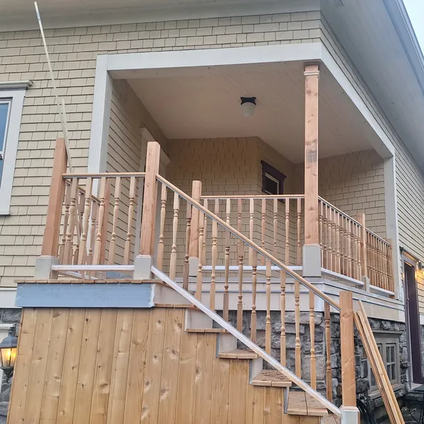 Finished porch with new wood railings, turned balusters and a staircase to the driveway