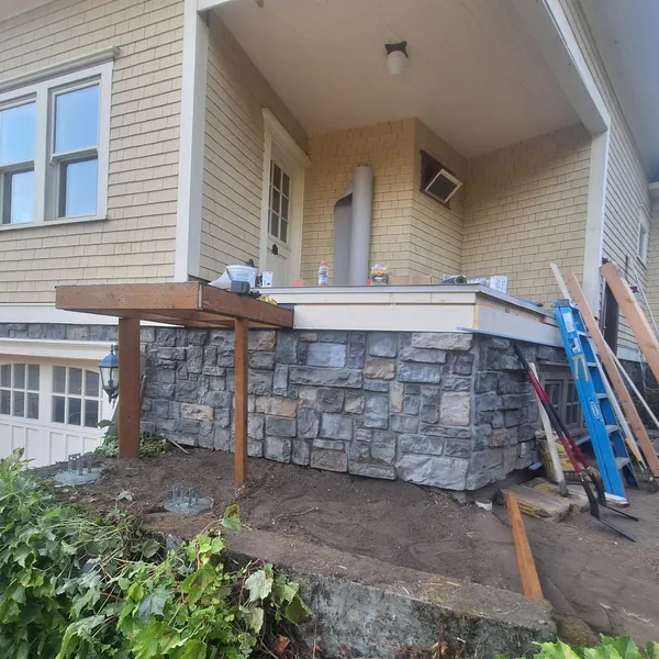 Porch framing and new stone skirting with the deck surface and railings still to come